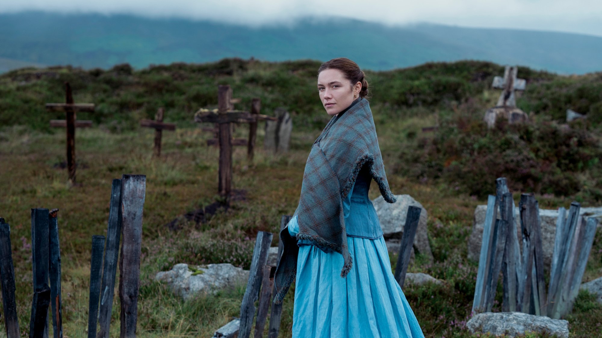 Florence Pugh stands in a graveyard in Ireland looking winsome in the film "The Wonder"