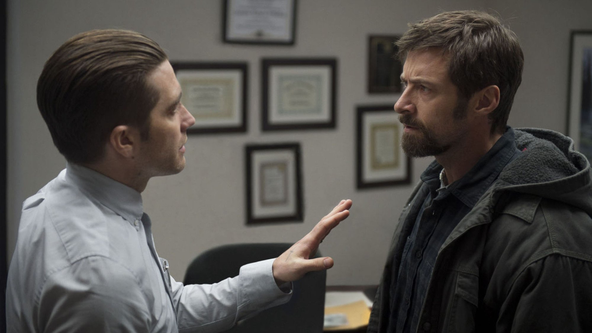 Jake Gyllenhaal tries to calm Hugh Jackman in a police station in the film "Prisoners"