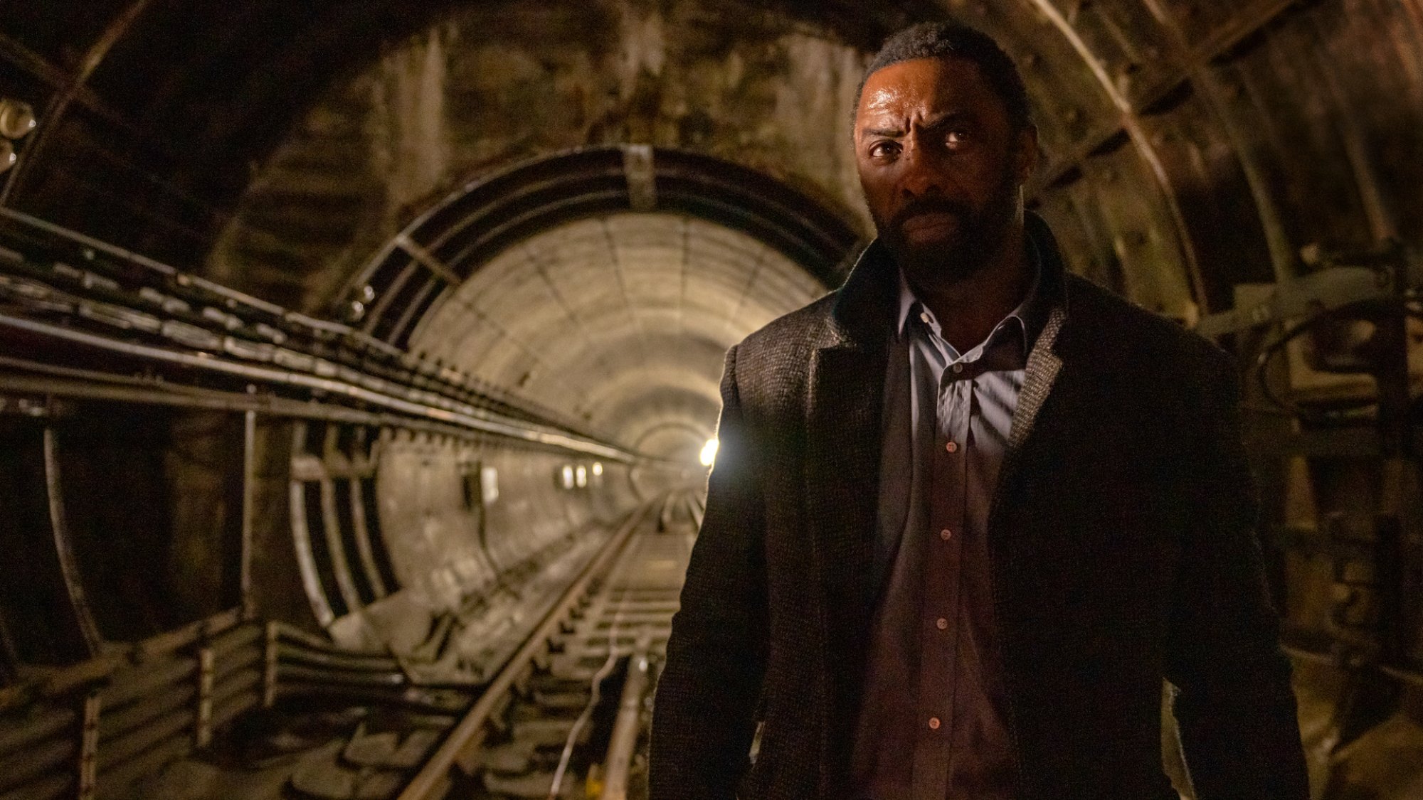 Idris Elba stands in an underground train tunnel in the film "Luther: The Fallen Sun"