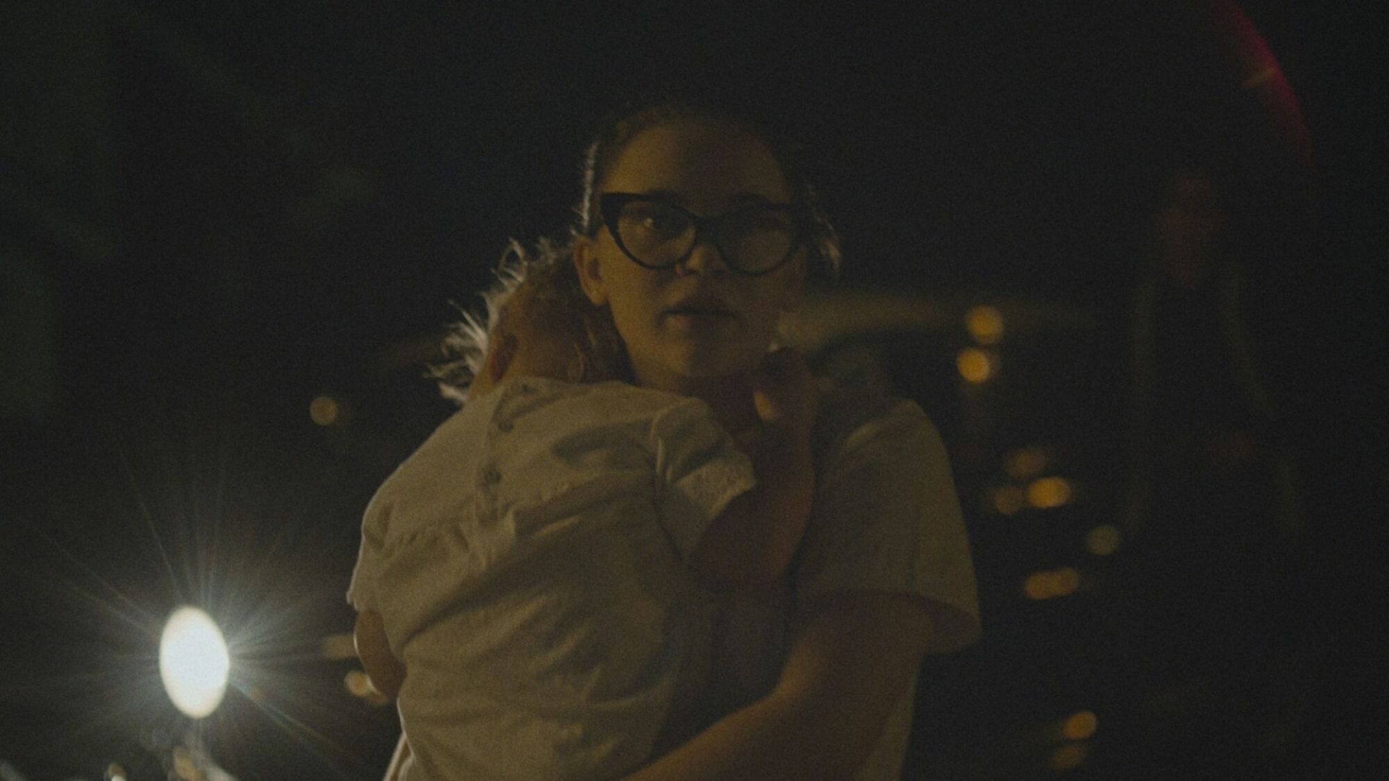 A teen girl carries a baby down a dark street in "The Vast of Night." 