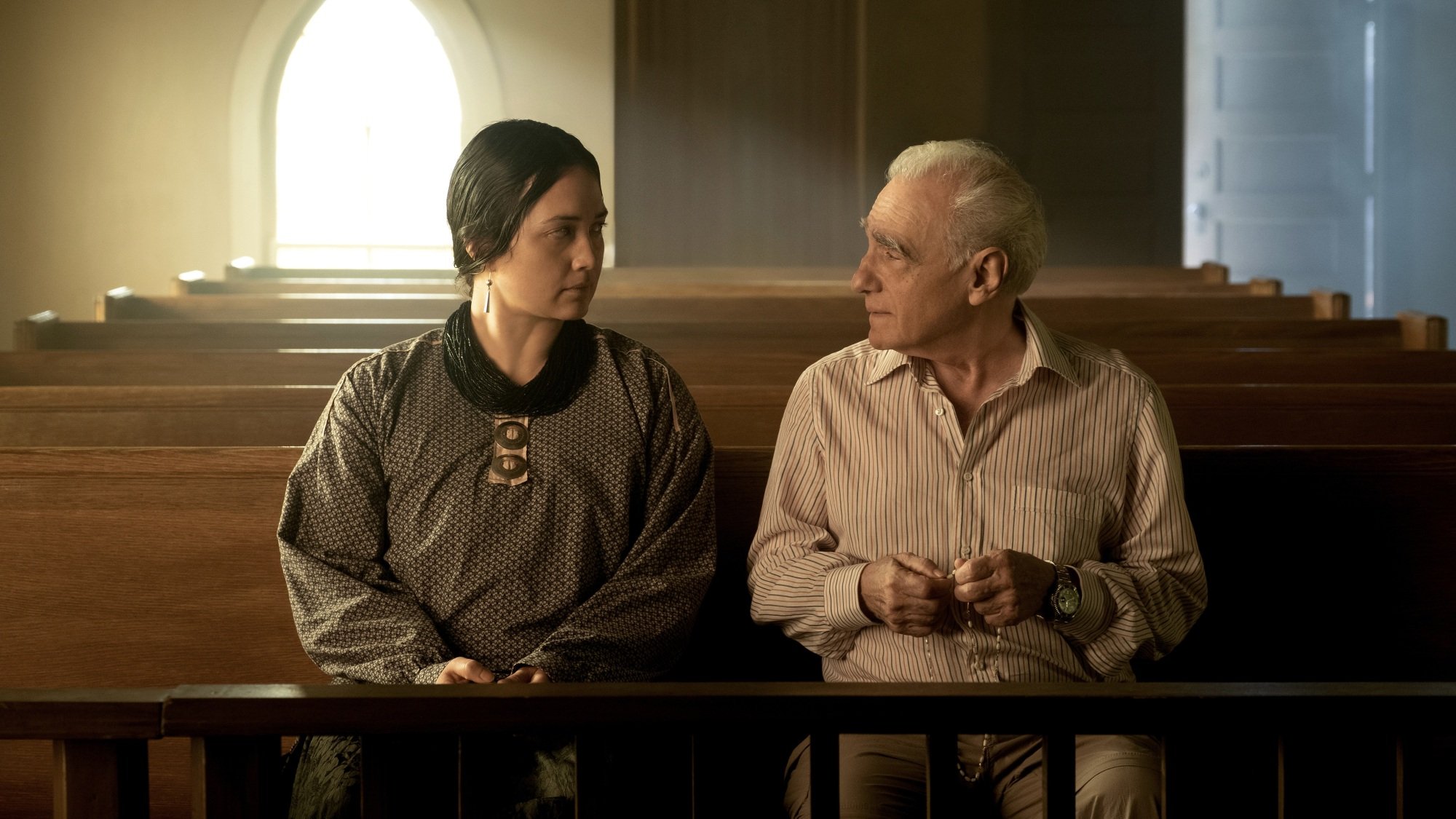 A man and woman sit in church pews.