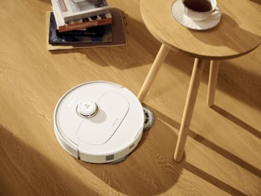 Roborock Q Revo robot vacuum mopping around table leg on hardwood floor