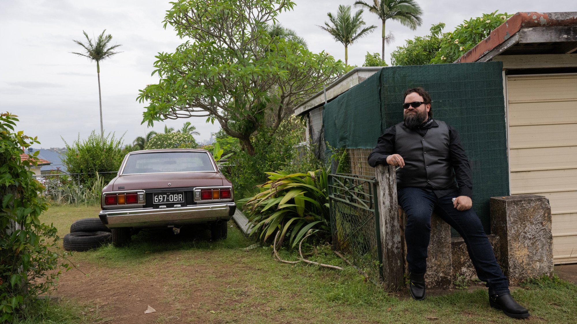 A man sits beside a driveway in a rural home.