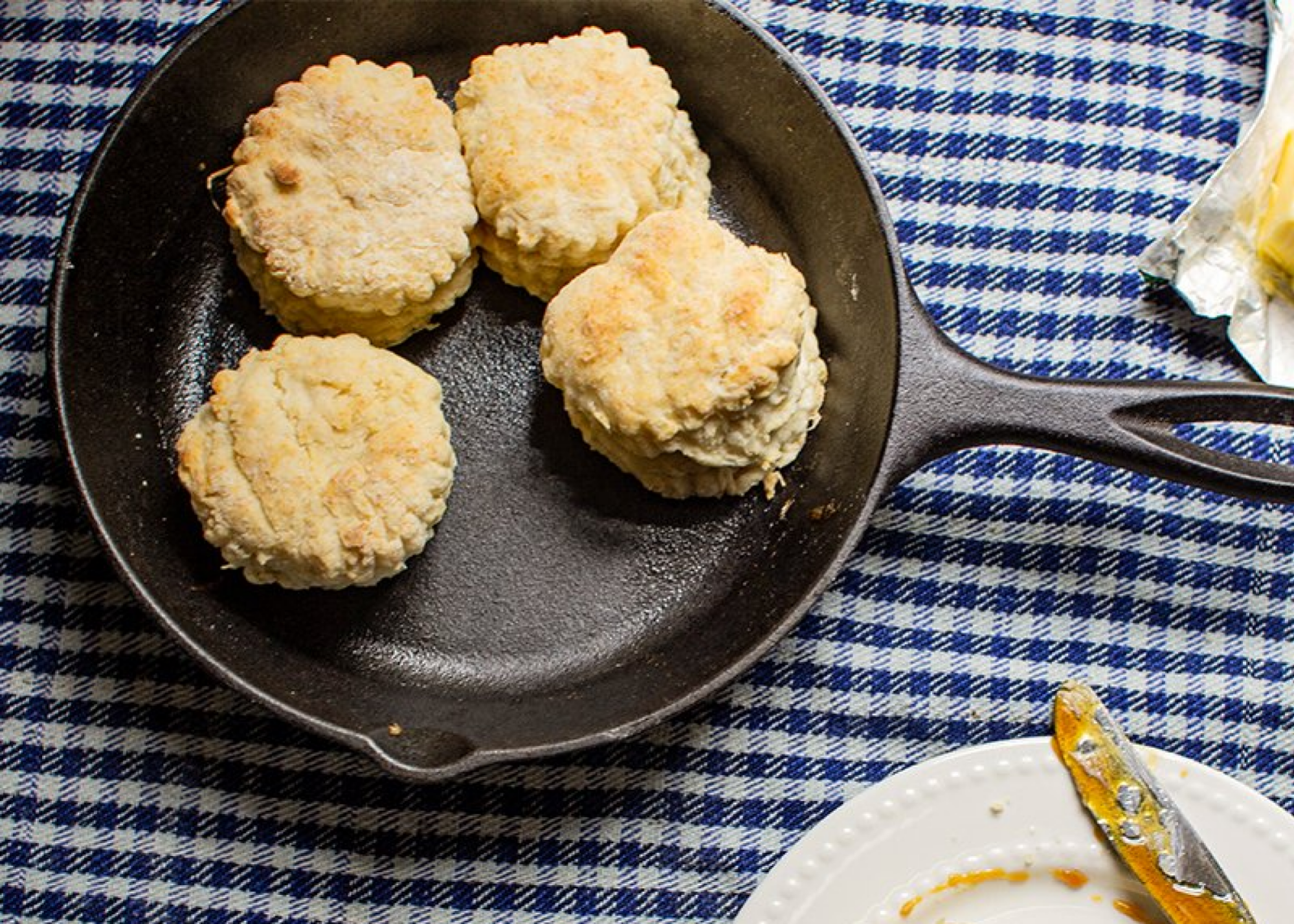 Lodge cast iron skillet with four biscuits on tablecloth