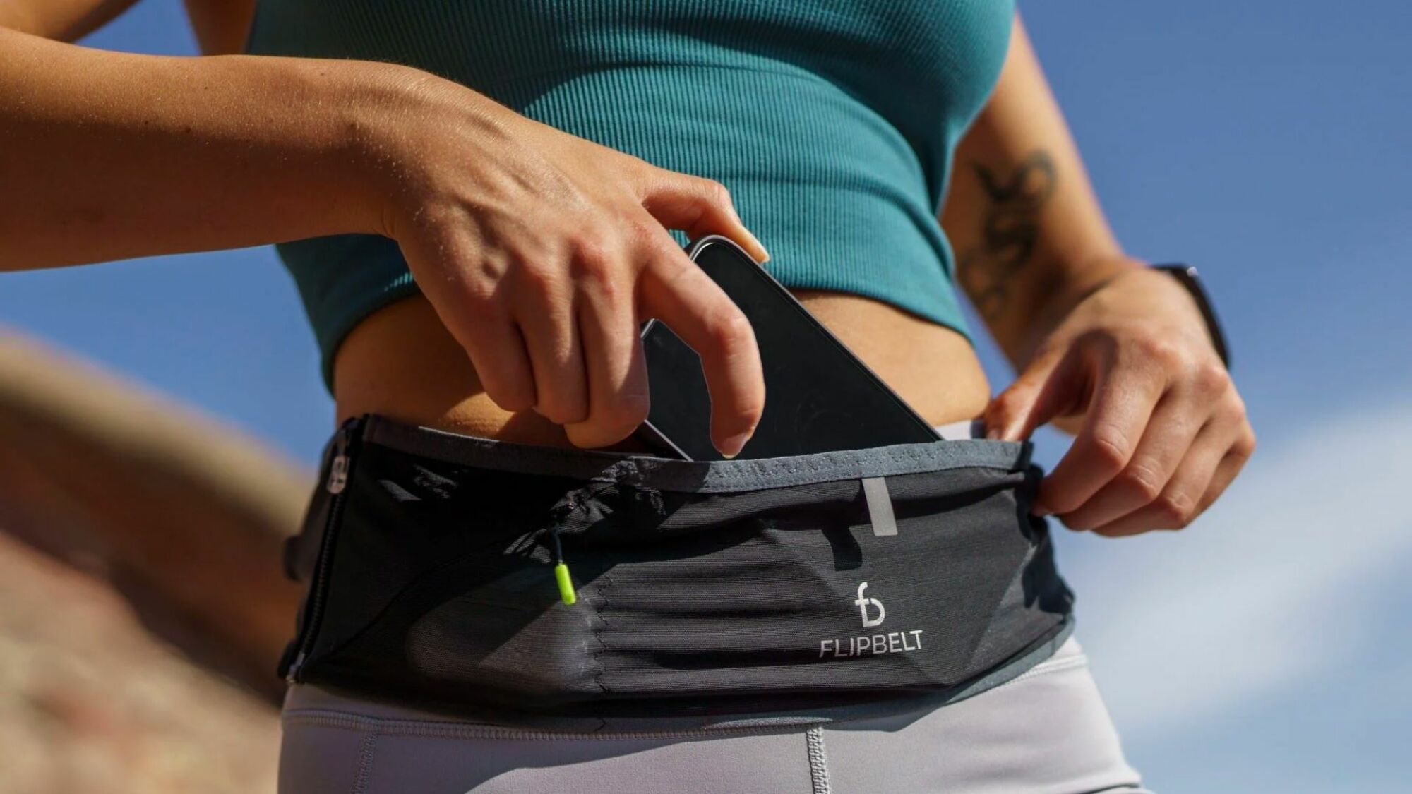 woman tucking phone into flipbelt fanny pack