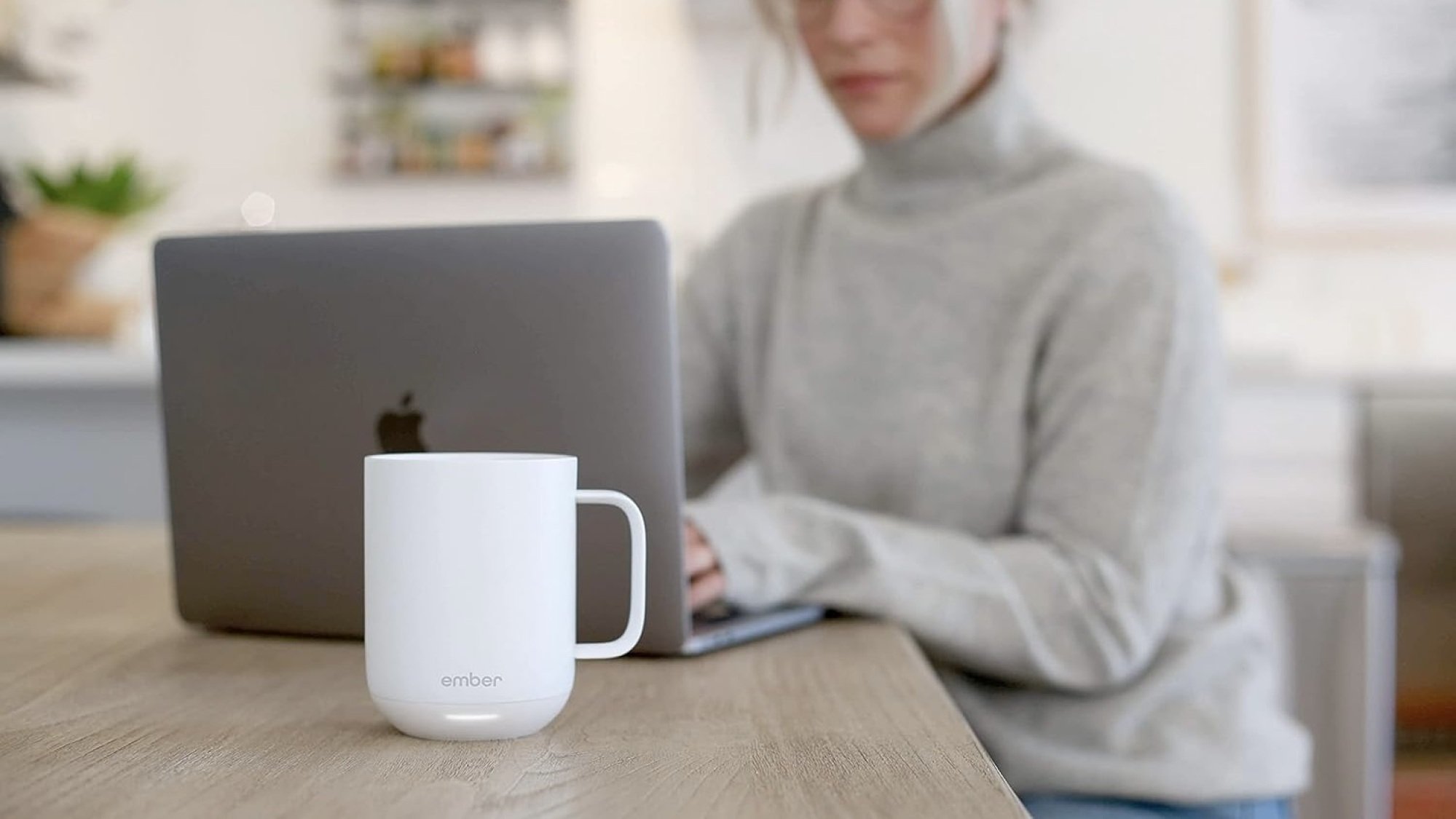 white ember mug sitting on desk of person working on laptop