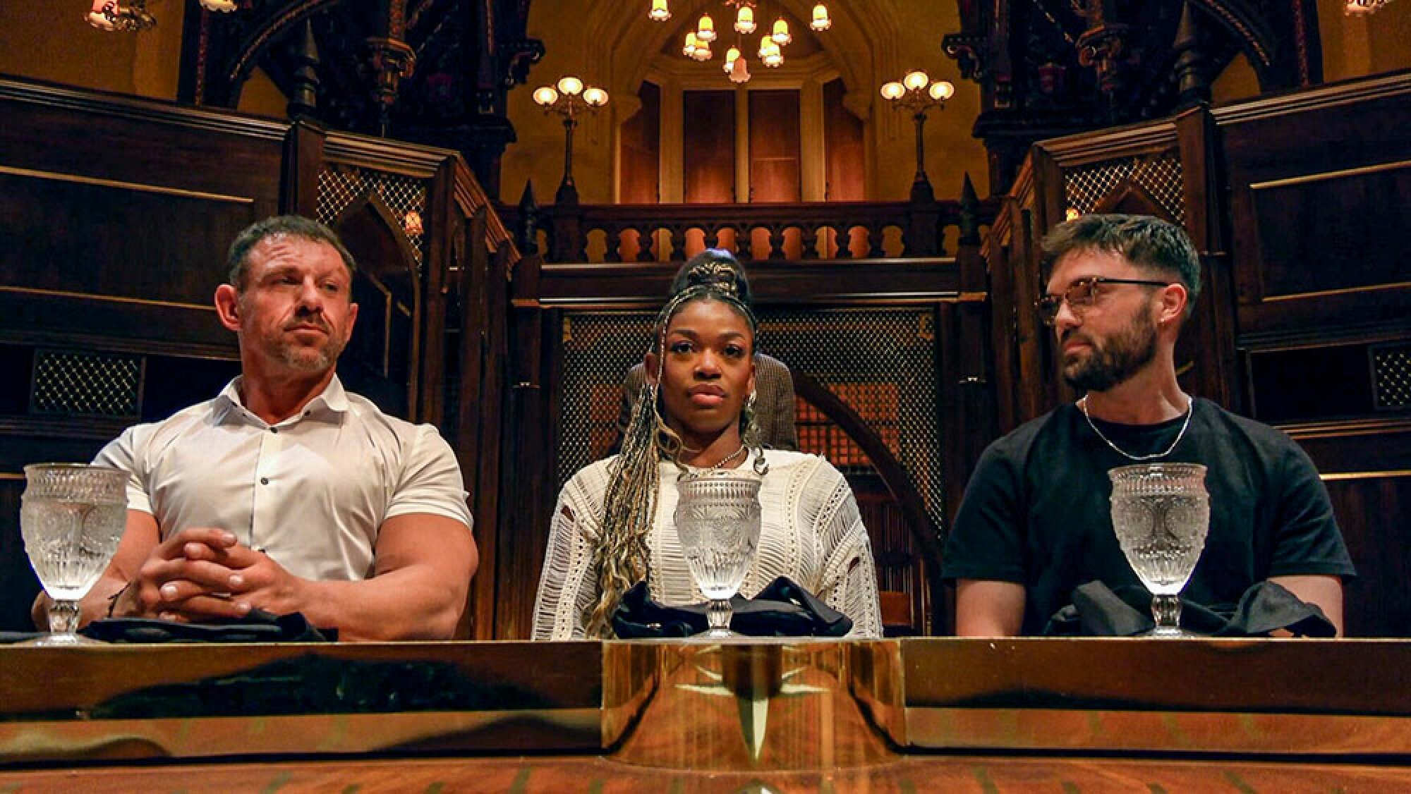 Two men and a woman sit at a large round table.