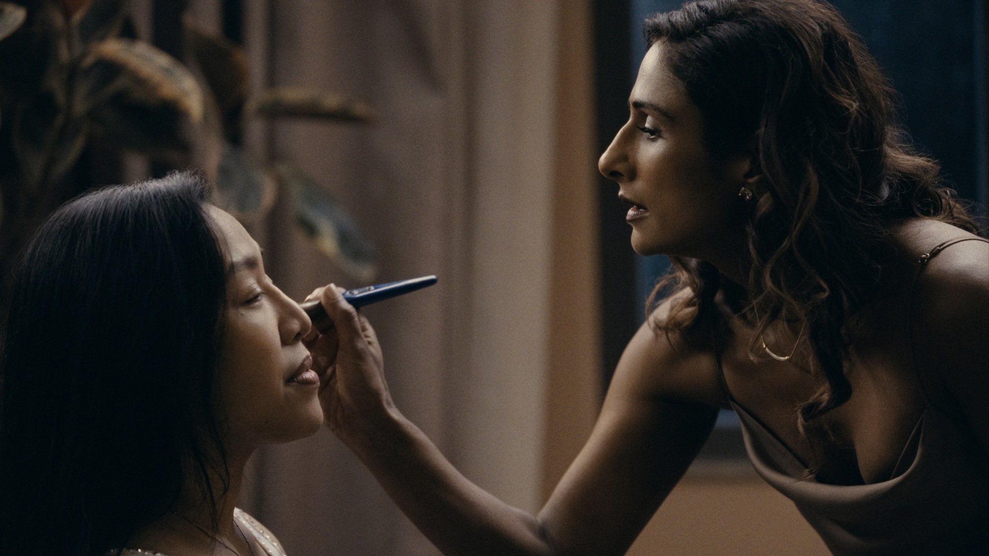 A woman applies makeup to another woman.