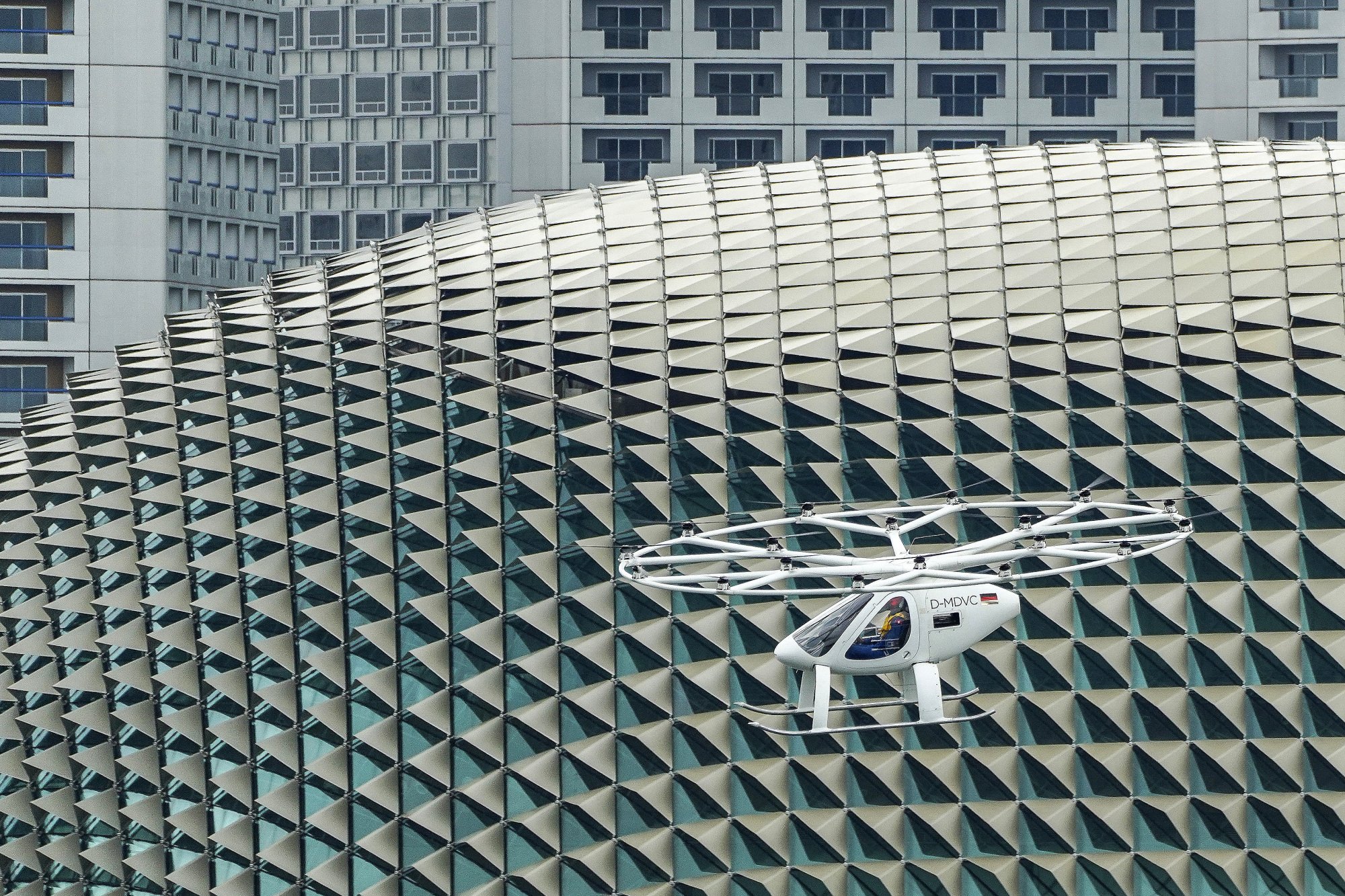 An electric air taxi seen from above, flying over tall buildings