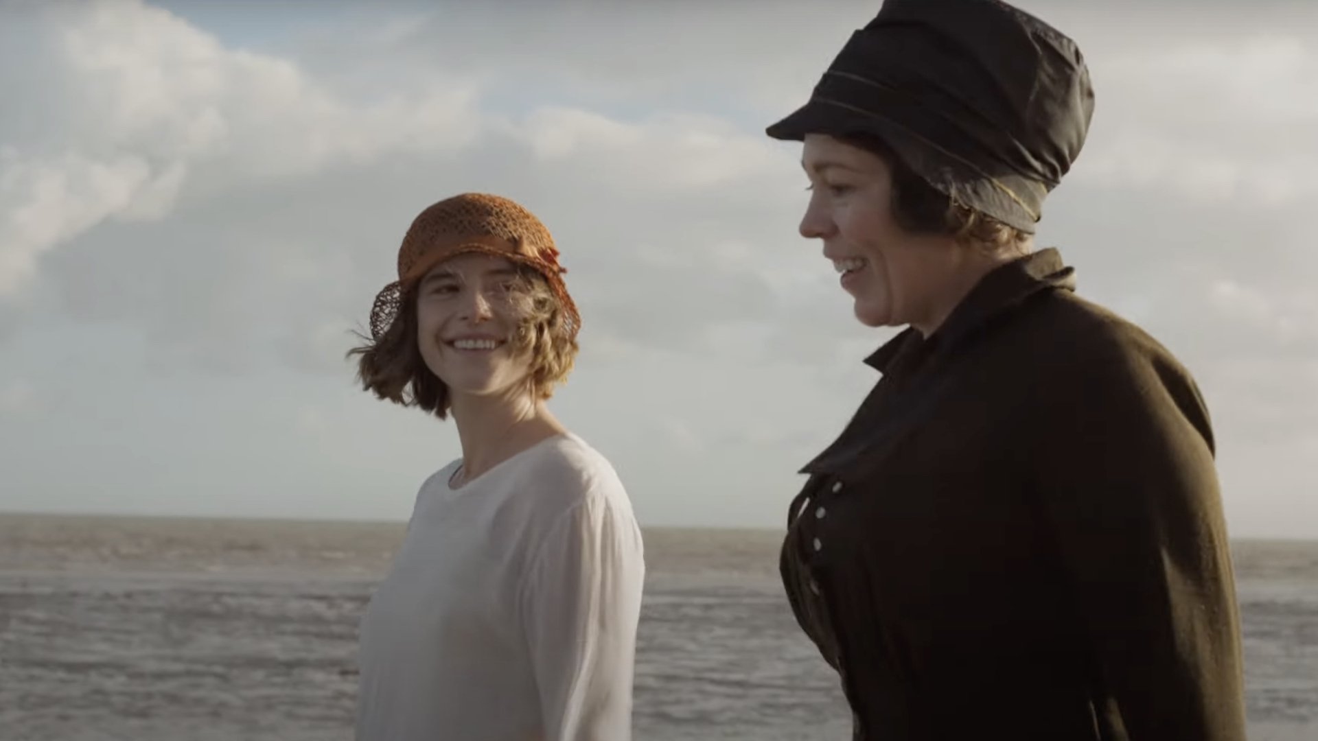 Two women stroll on the beach.