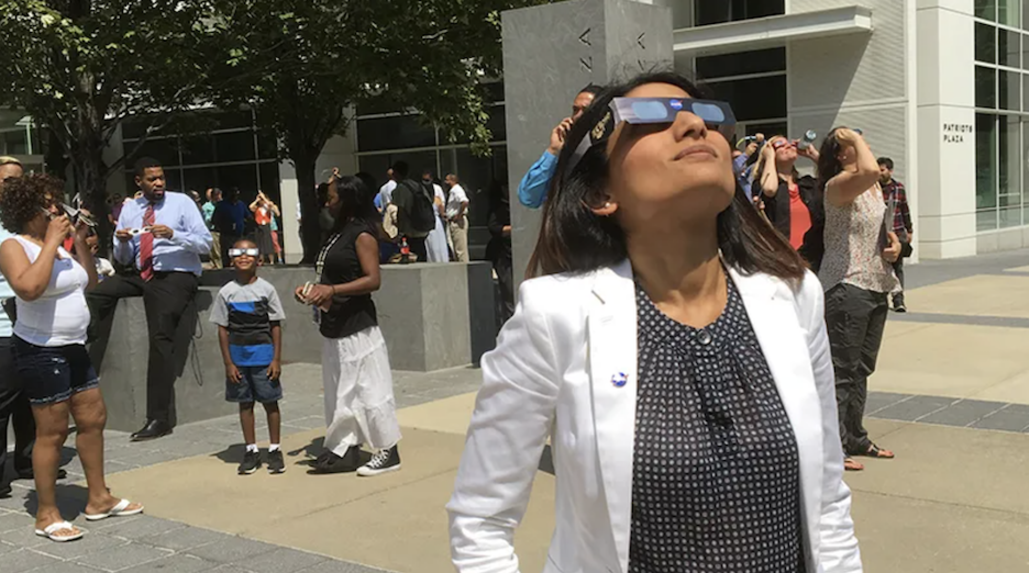 A woman views the eclipse with eclipse glasses.