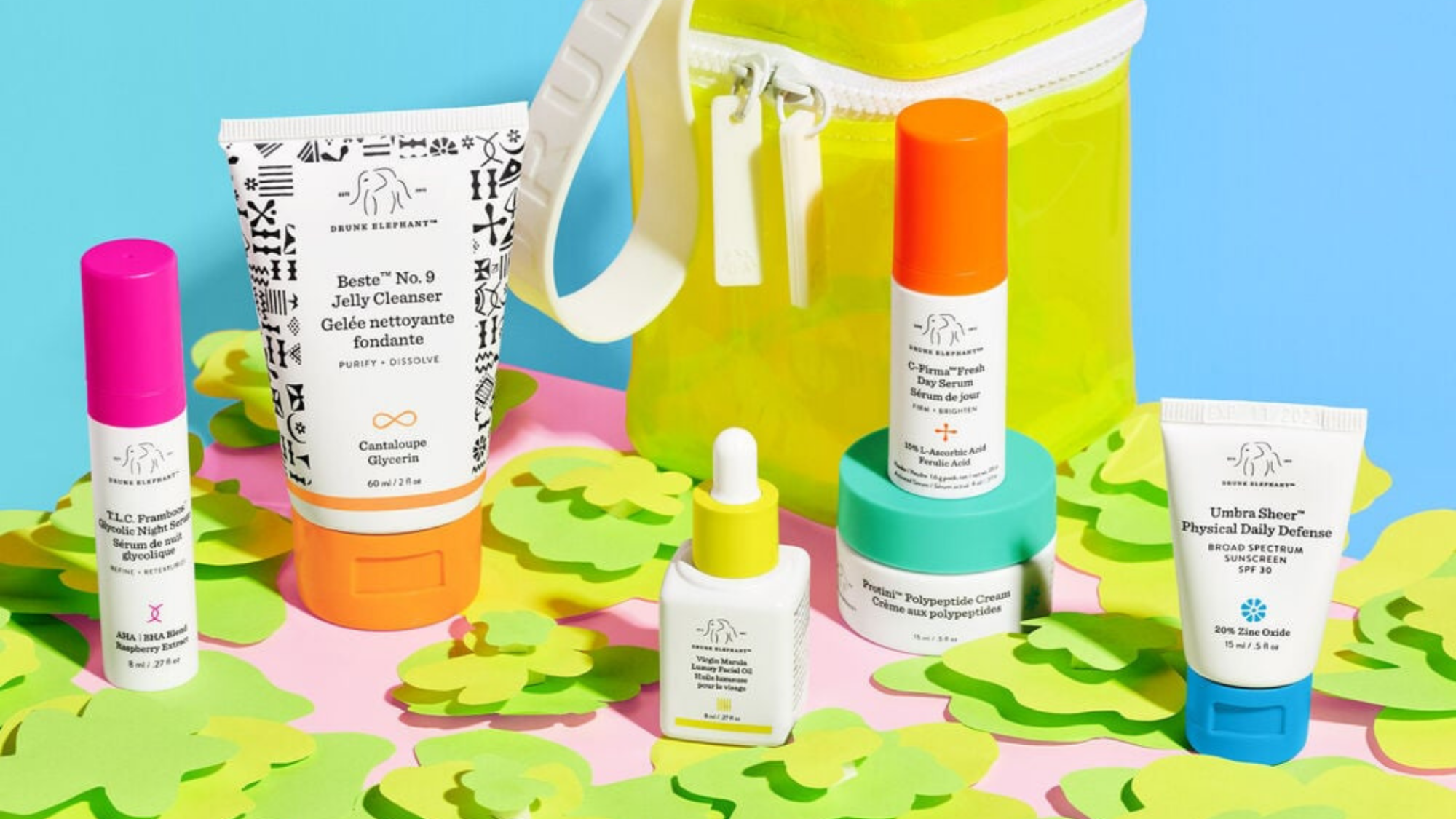 Five Drunk Elephant products with neon coloring: hot pink, orange, yellow, dark orange, and teal. 