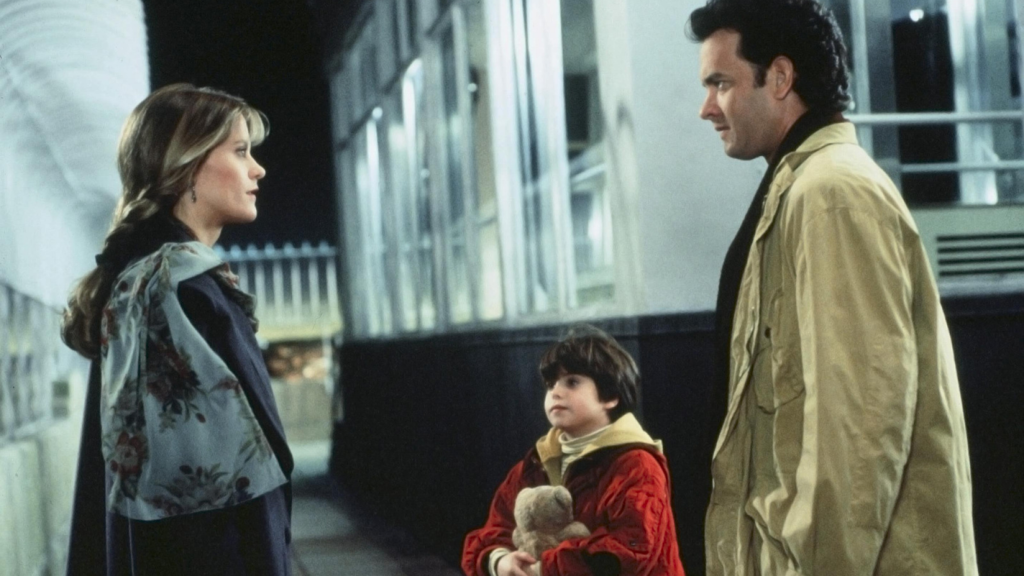 A man, woman, and young boy wearing raincoats talk. 