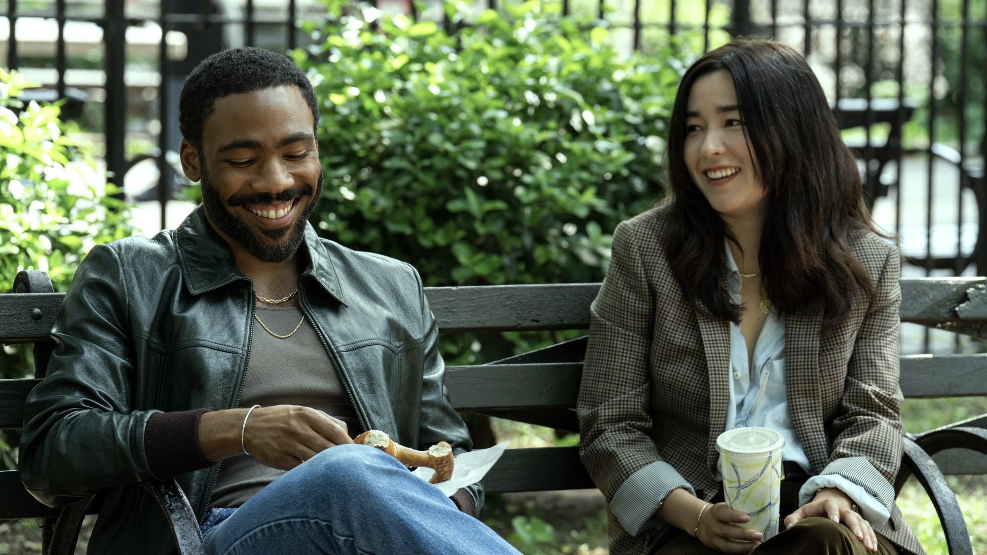 A man and woman laughing together on a park bench.