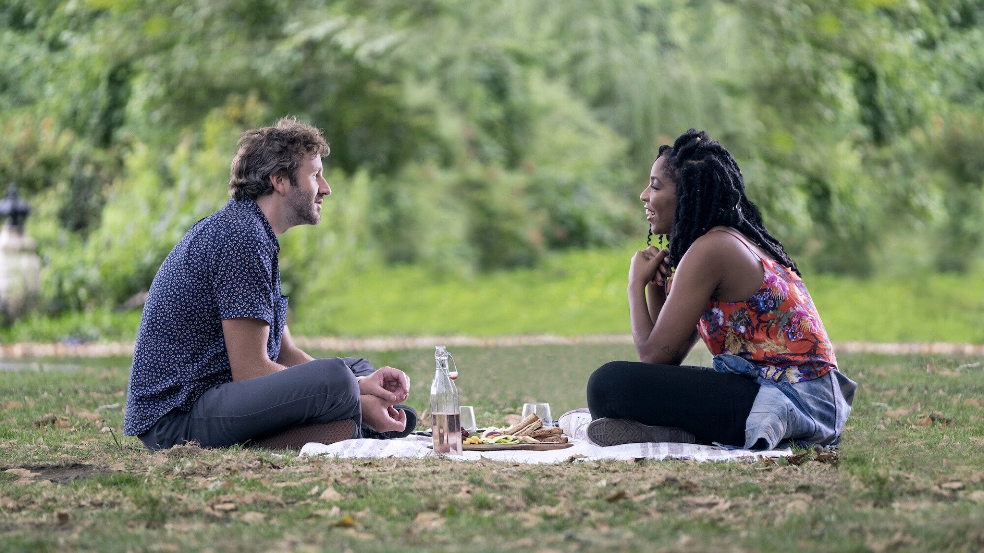 A man and woman have a picnic in a park.