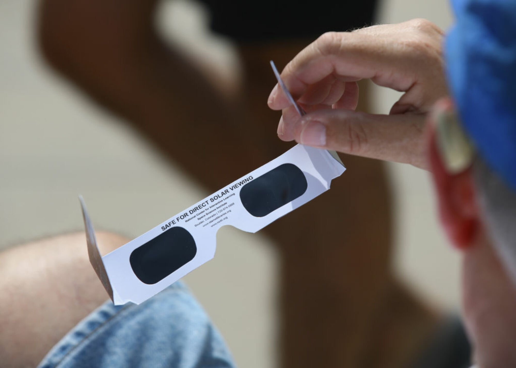 Spectator holding solar eclipse glasses