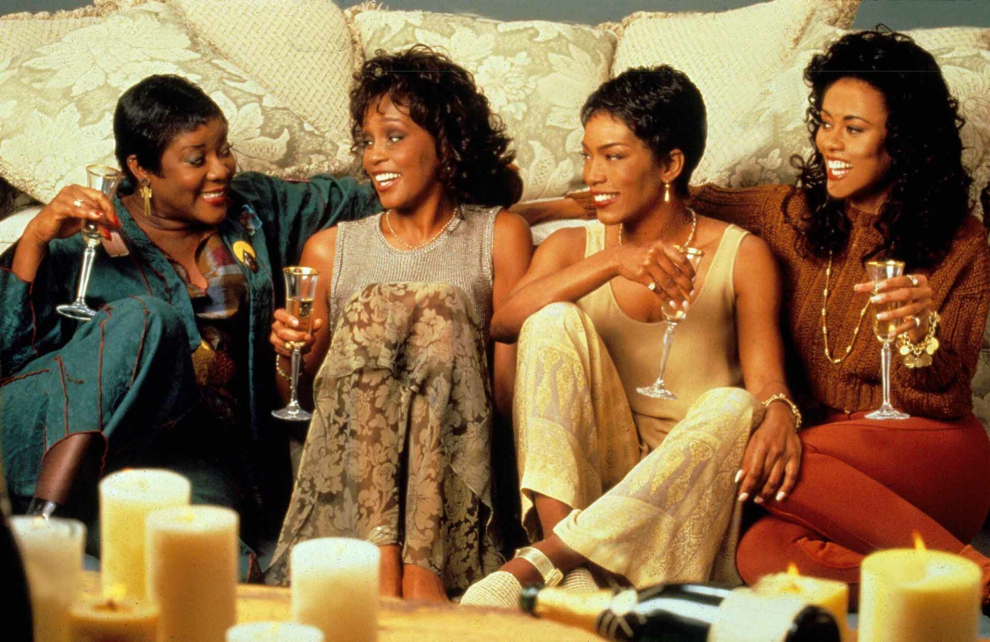 Four Black women sit on a couch holding wine and looking at each other in "Waiting to Exhale."