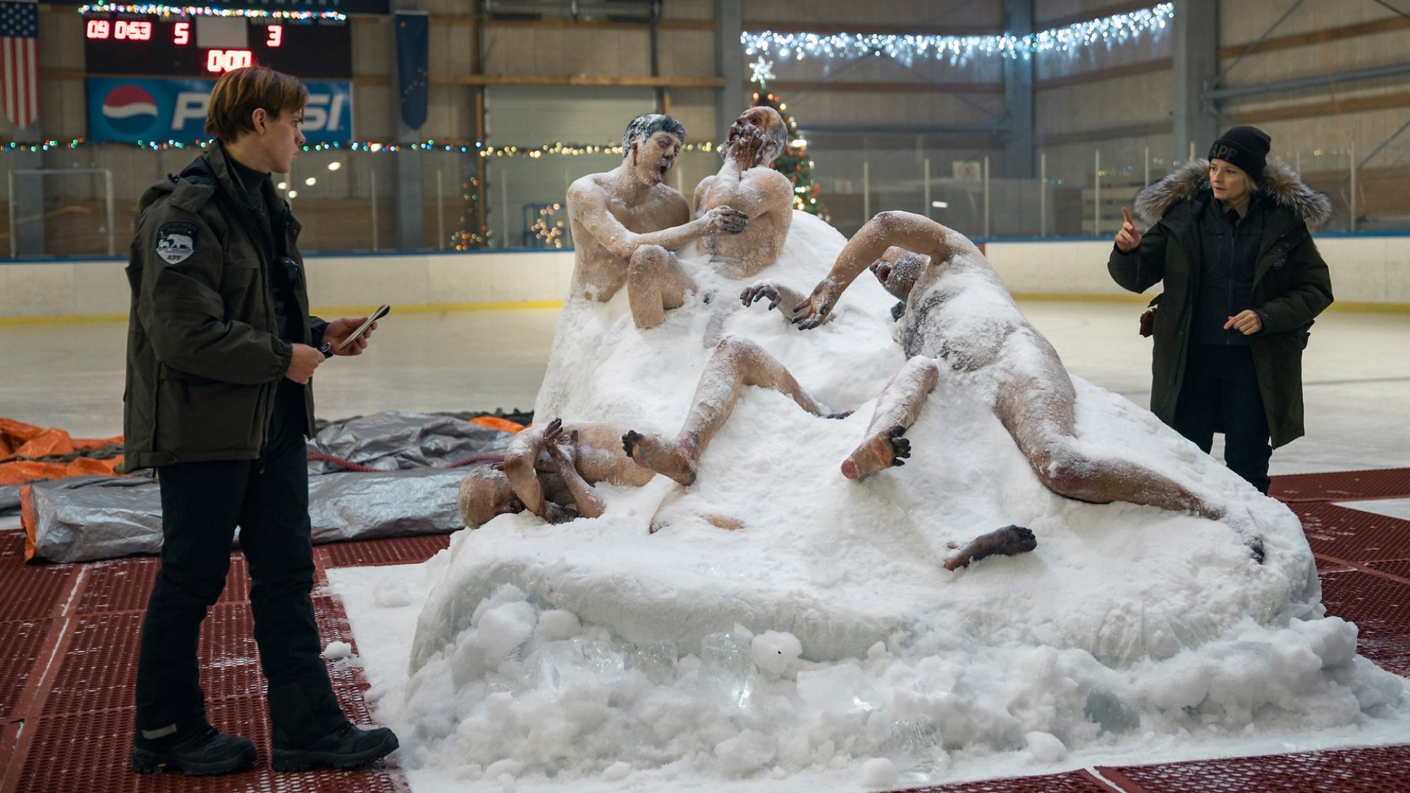 Two cops stand around a frozen mass of bodies.