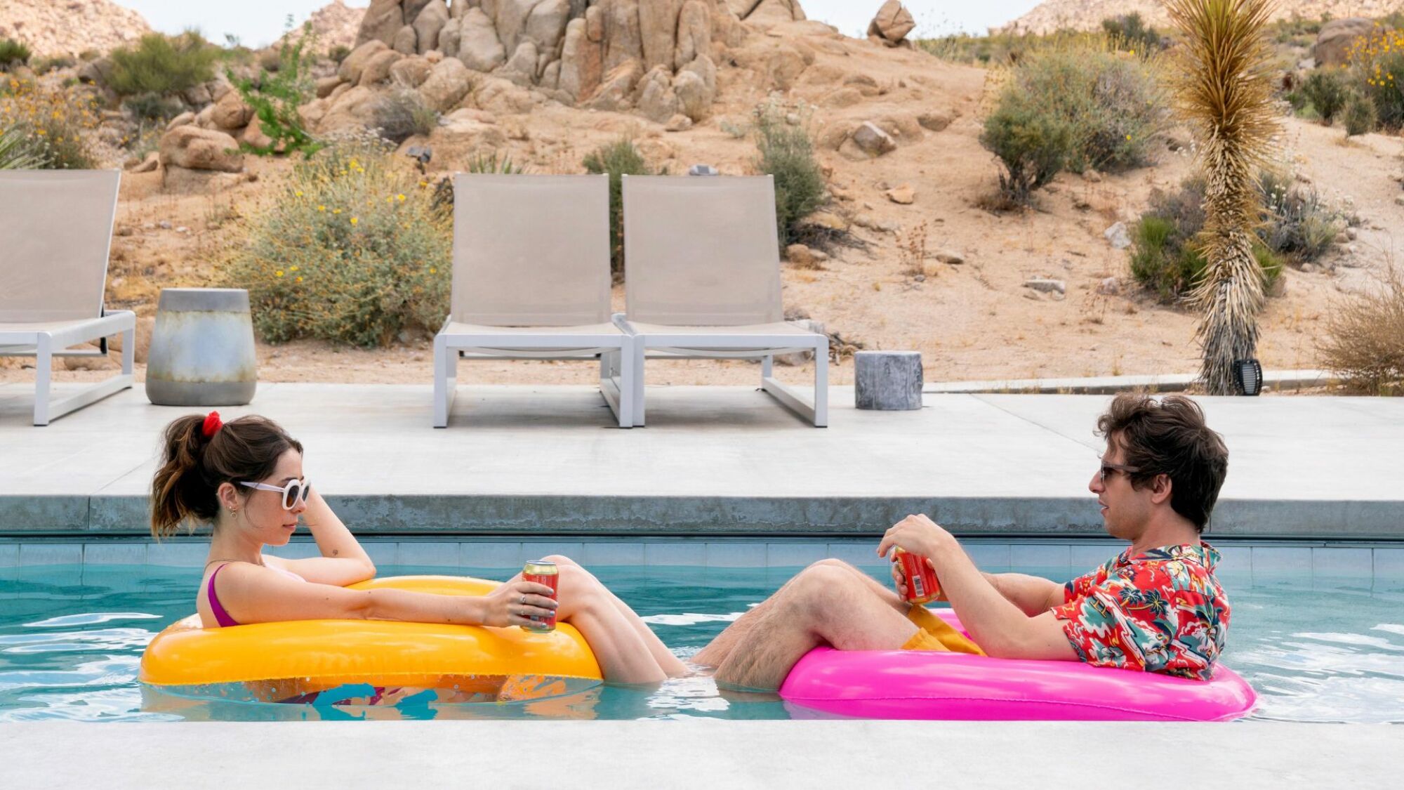 A man and woman float in a pool. 