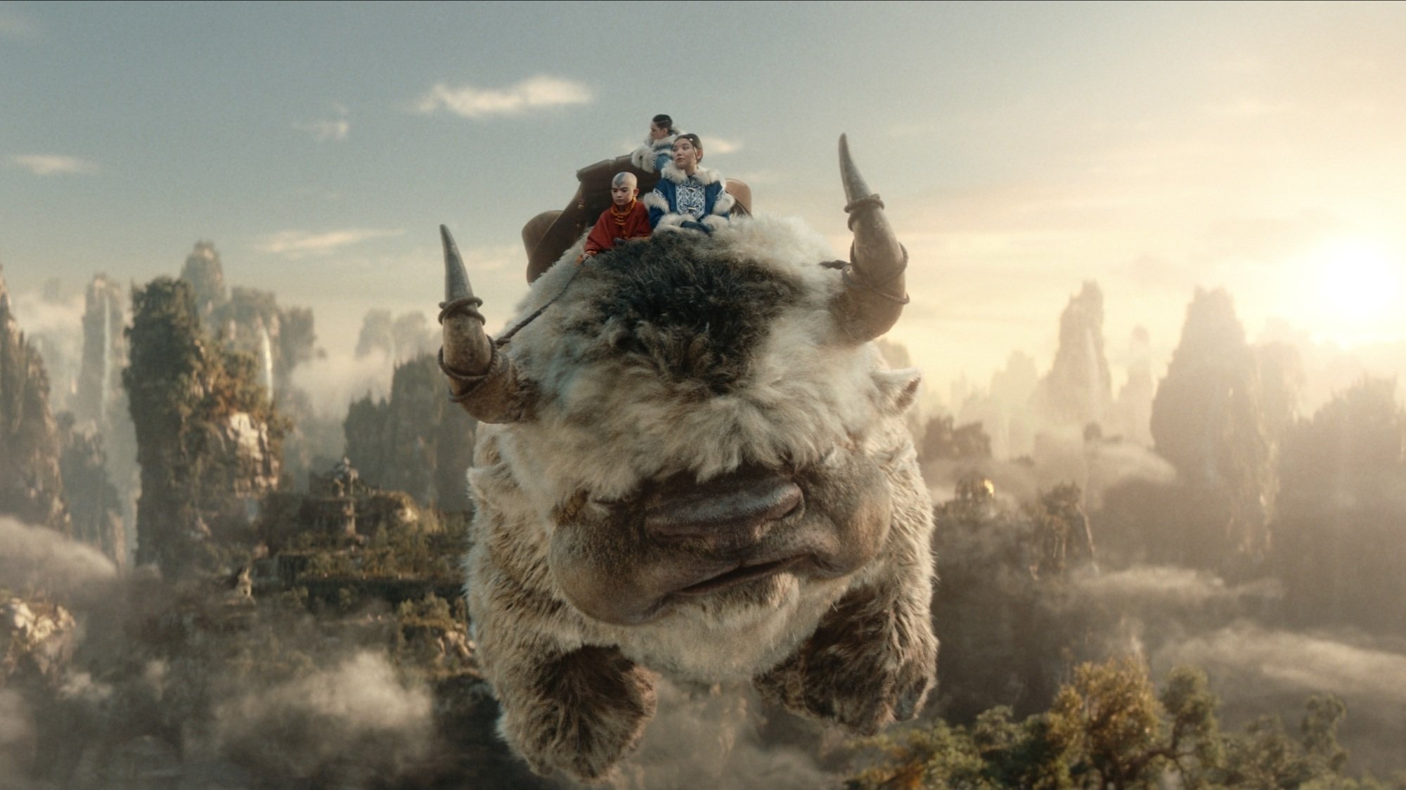 Appa the sky bison flying through the sky with Aang, Katara, and Sokka on his back.