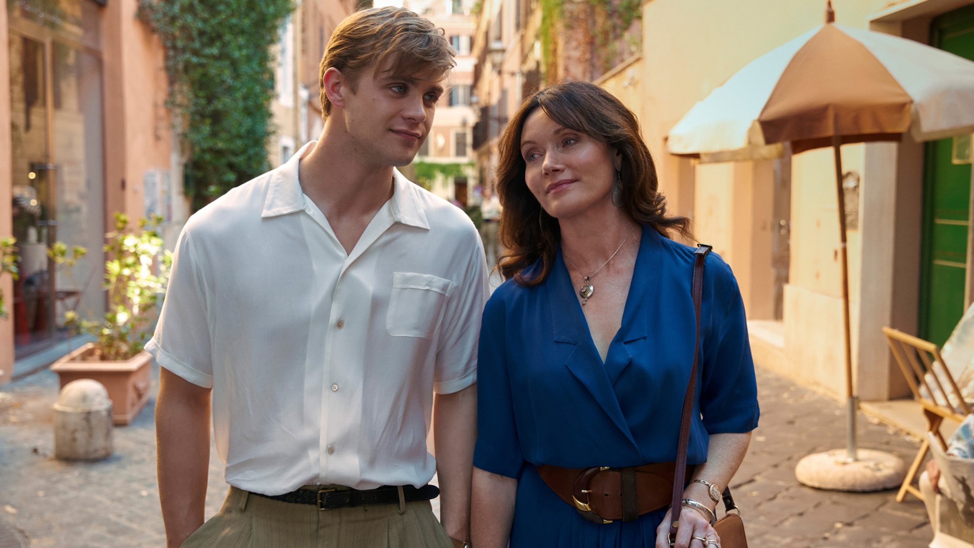 Two well dressed people take a leisurely stroll through an Italian street.