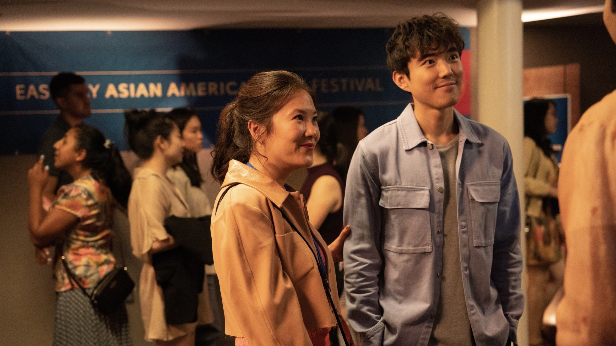 A man and woman in a crowded movie theater lobby.