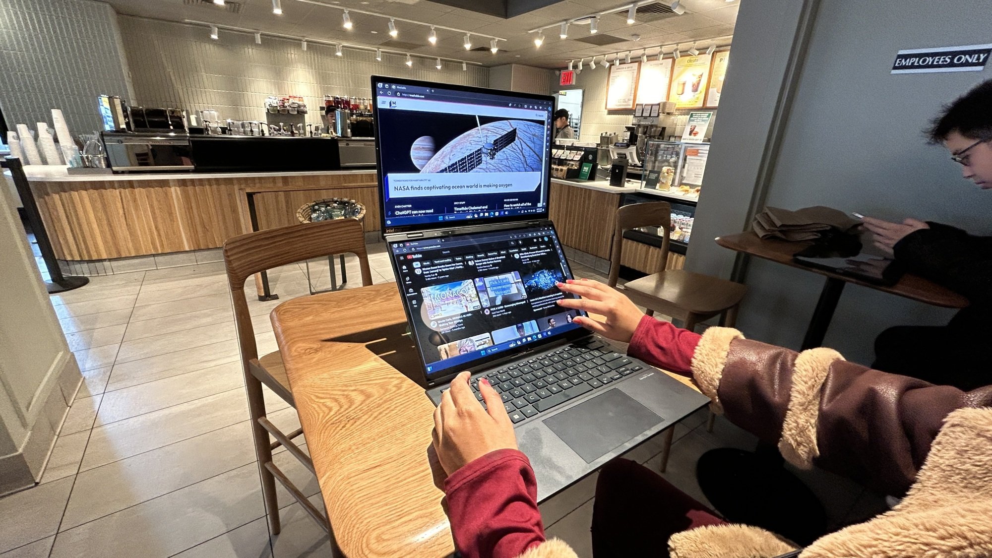 Asus Zenbook Duo juggling two apps with woman's fingers interacting with it