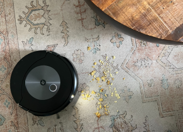 iRobot robot vacuum using light to clean chip crumbs off rug