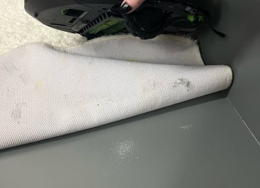 Person holding robot vacuum above folded bath mat