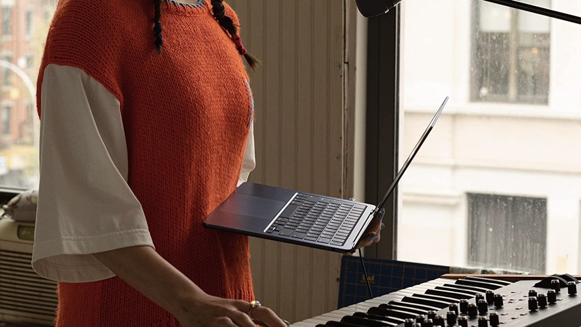 person holding m2 macbook air in front of piano