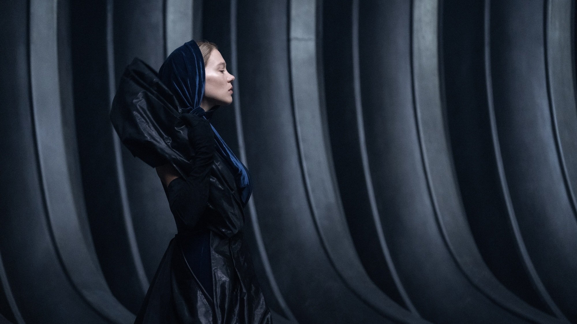 Lady Fenring walks through a dark hallway.