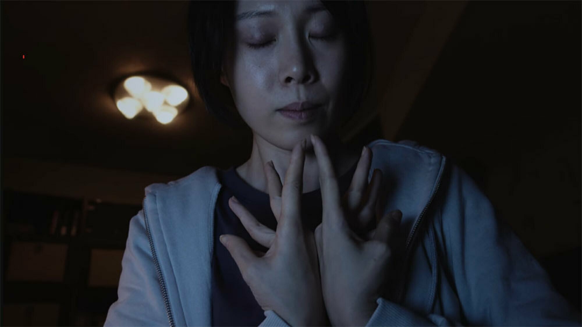 A woman holds her hands in prayer.