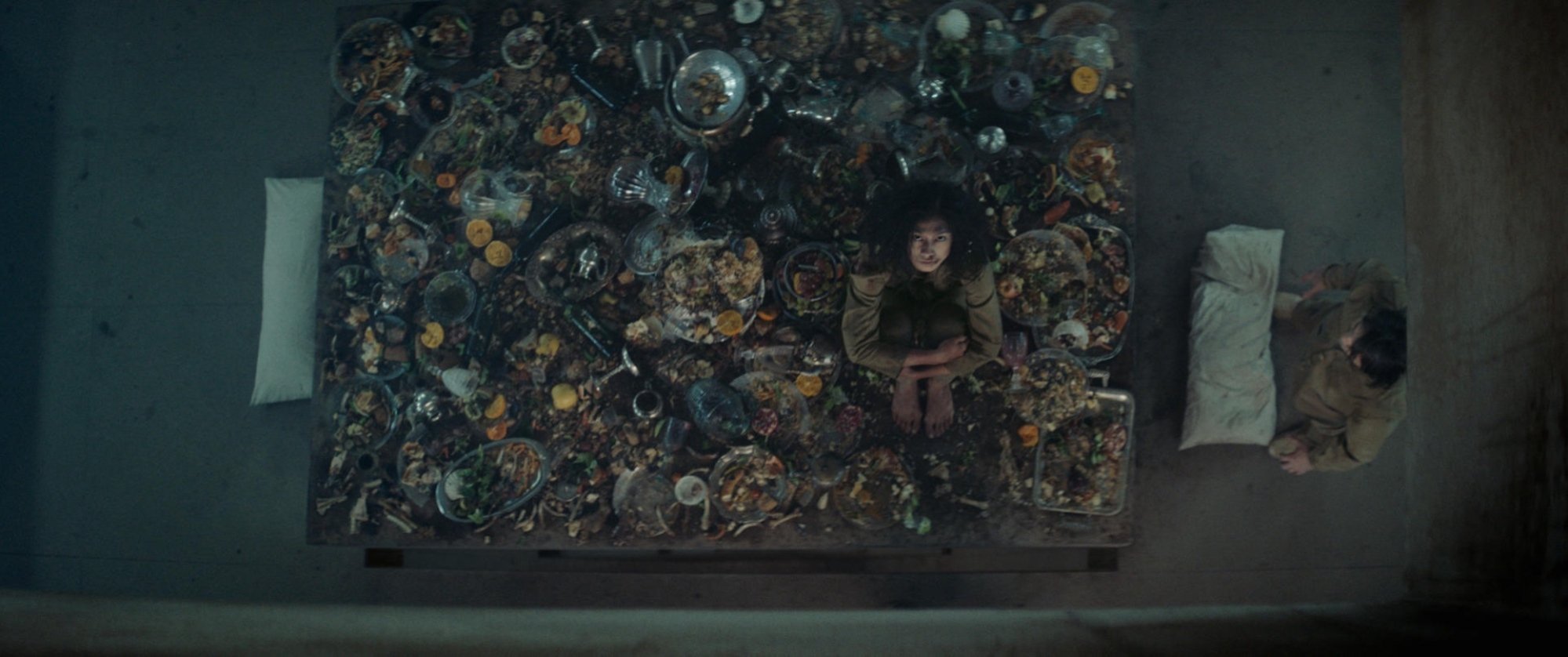 A woman sits on a filthy, food-covered table top.
