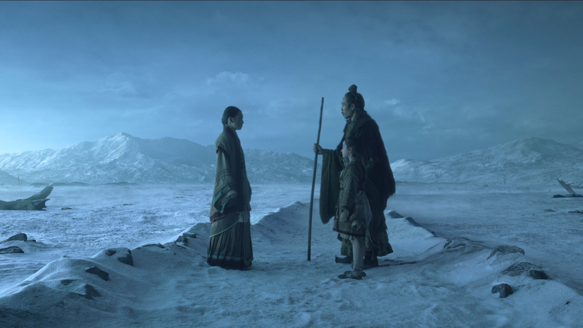 Three people wearing outfits from an ancient Chinese dynasty stand in a desert at night.