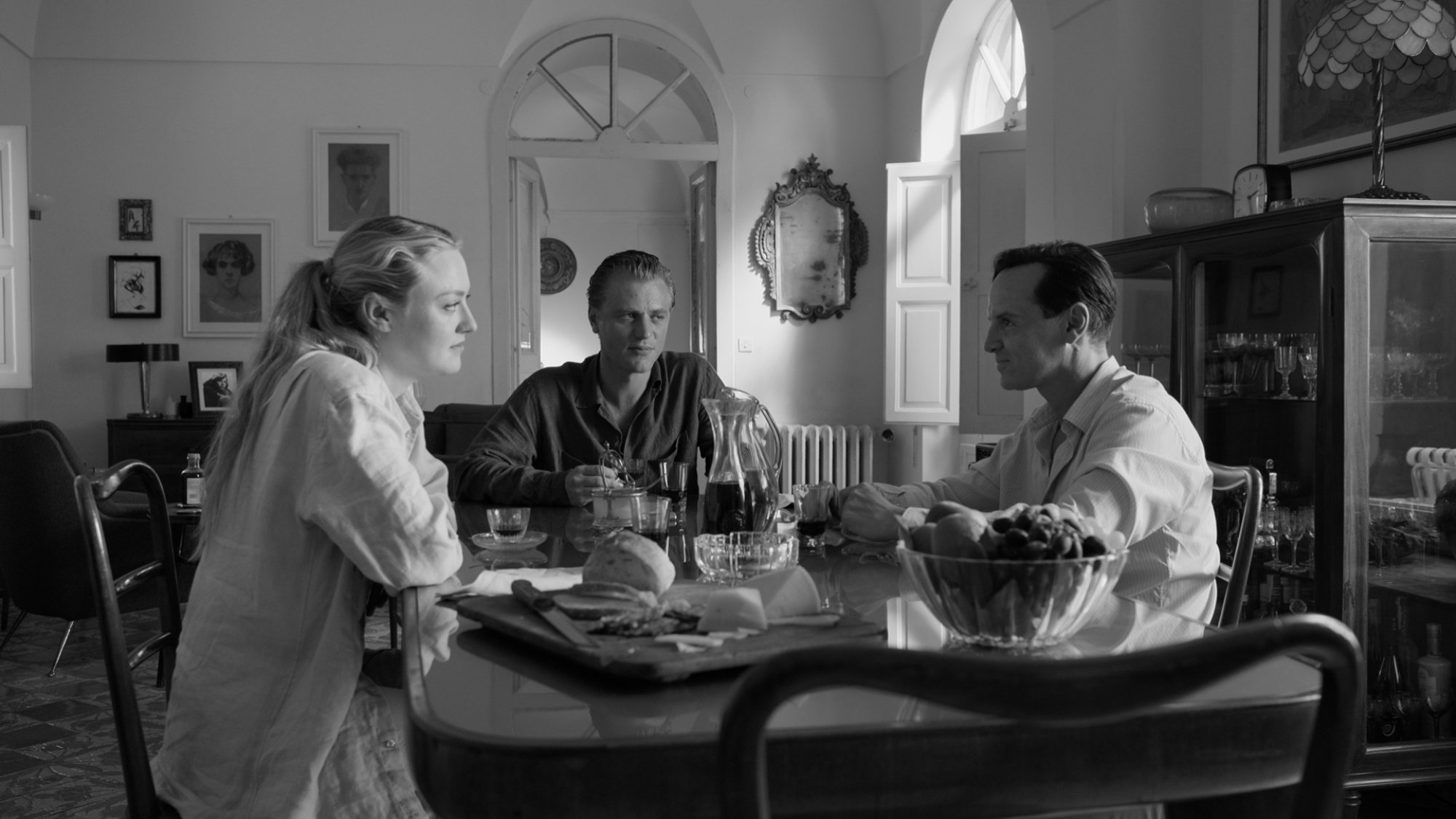 Three people eat at an opulent dining table.