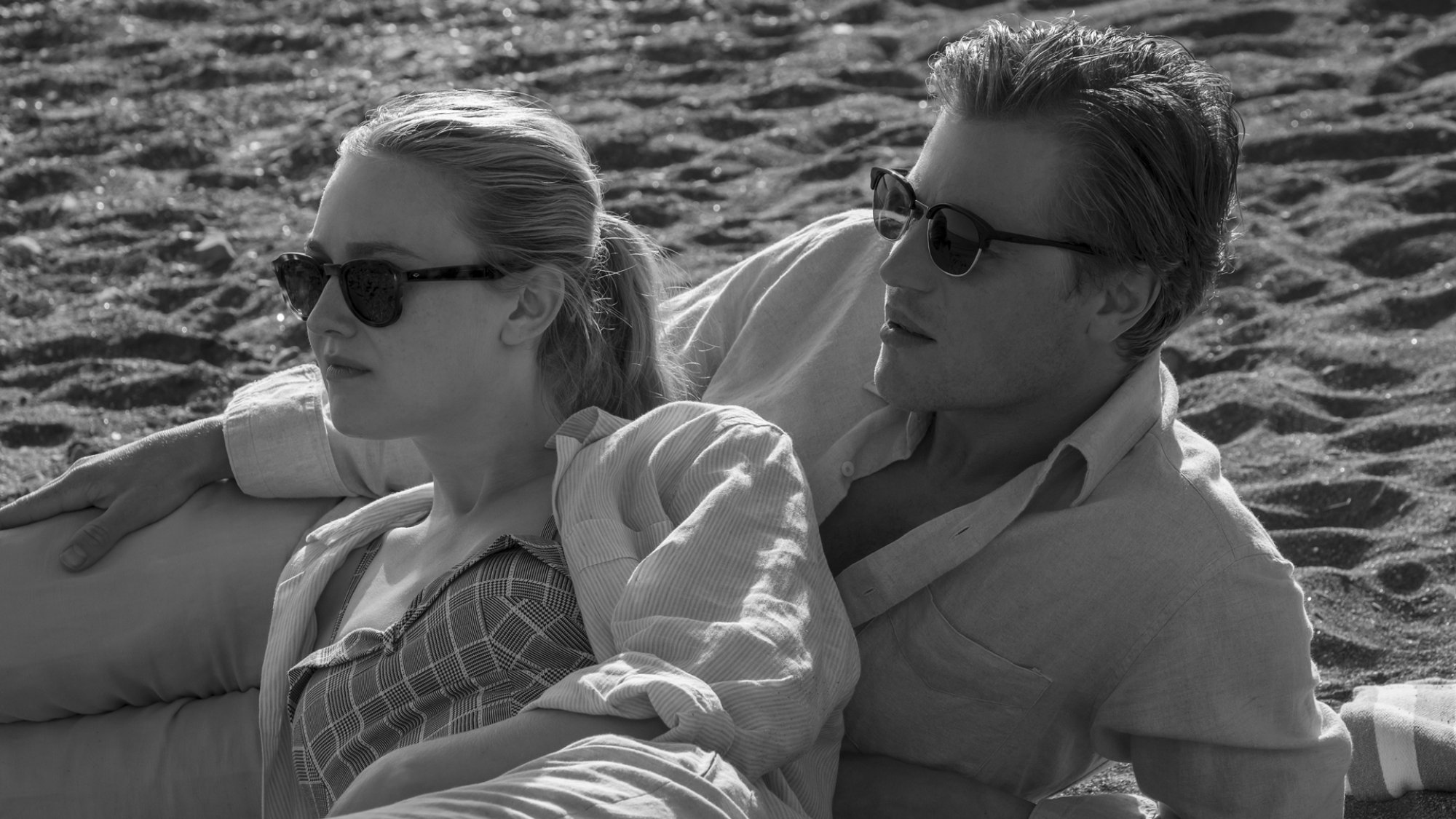 Two glamorous people with sunglasses relax on a yacht.