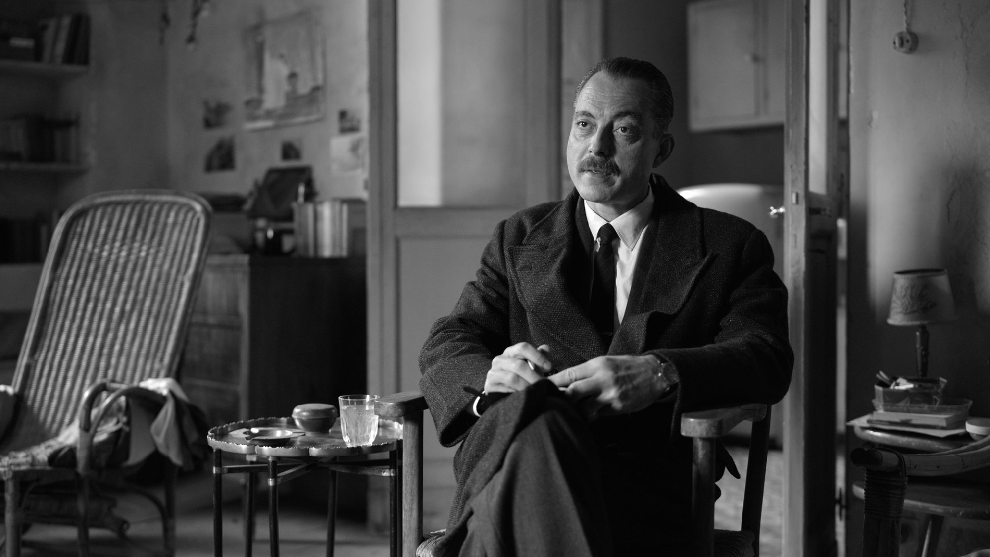 A man in a suit takes notes in an opulent living room.