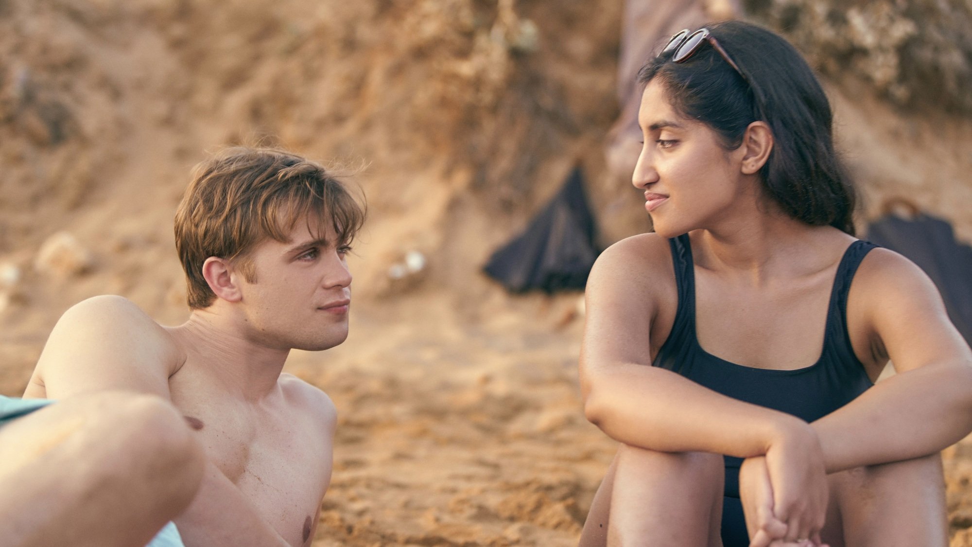 A man and a woman on a beach looking at each other.