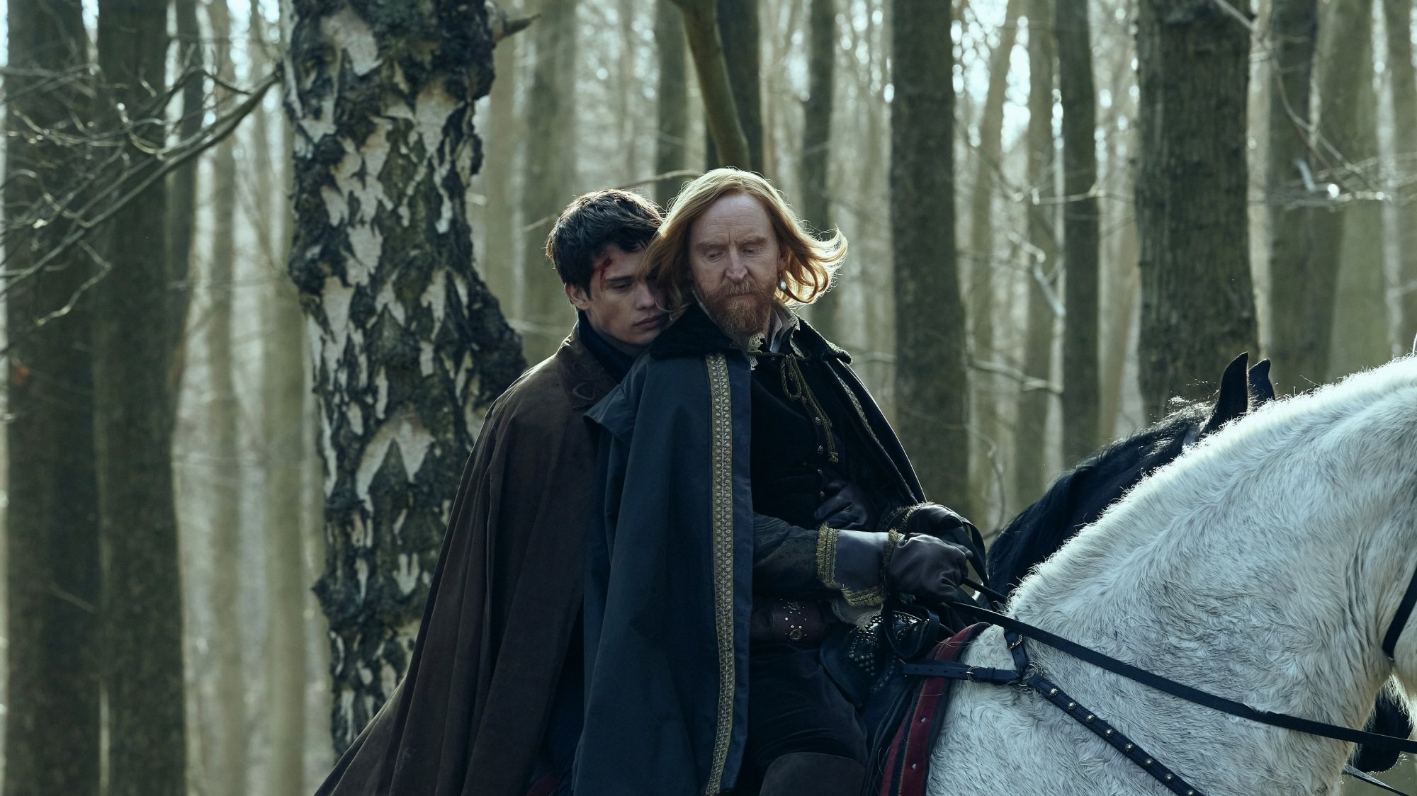 George Villiers and King James VI and I riding on the back of a white horse through the woods.
