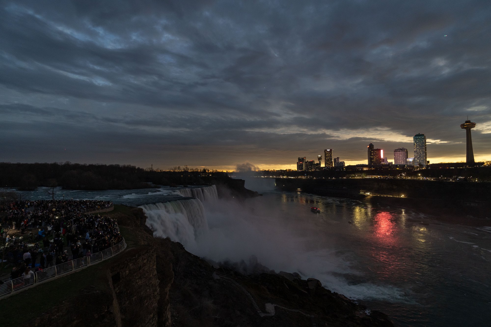 People gather to watch totality during the Solar Eclipse in Niagara. There is light orange light and near total darknes.