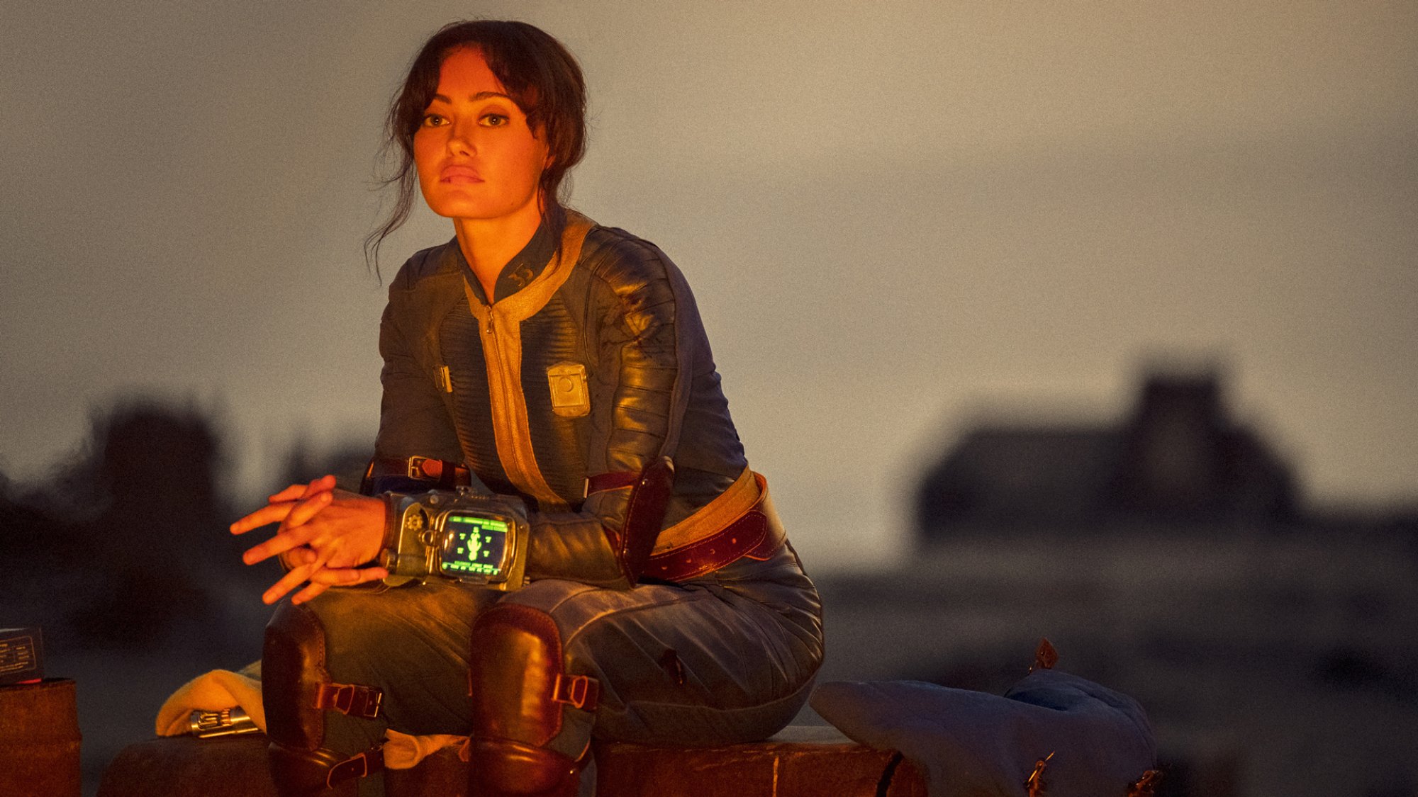 Ella Purnell sits by a fire alone as Lucy in the "Fallout" series.