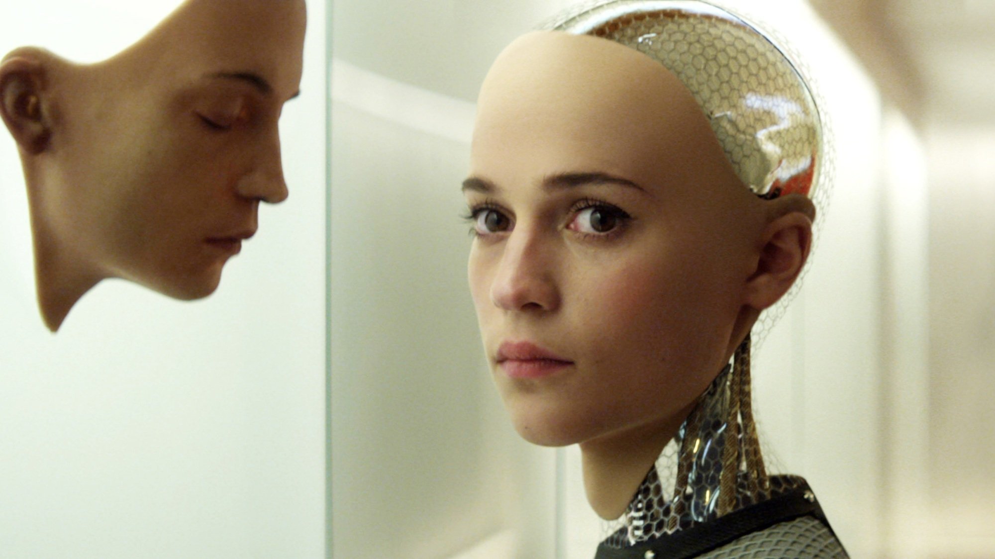 A humanoid robot woman looks at a human face mask.