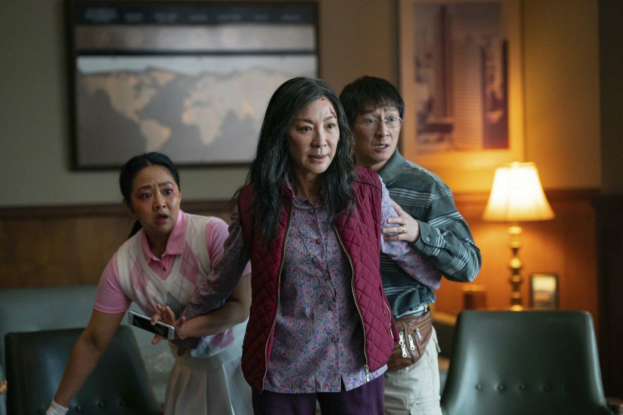 An Asian woman holds her husband and daughter back; they look scared while she looks determined.