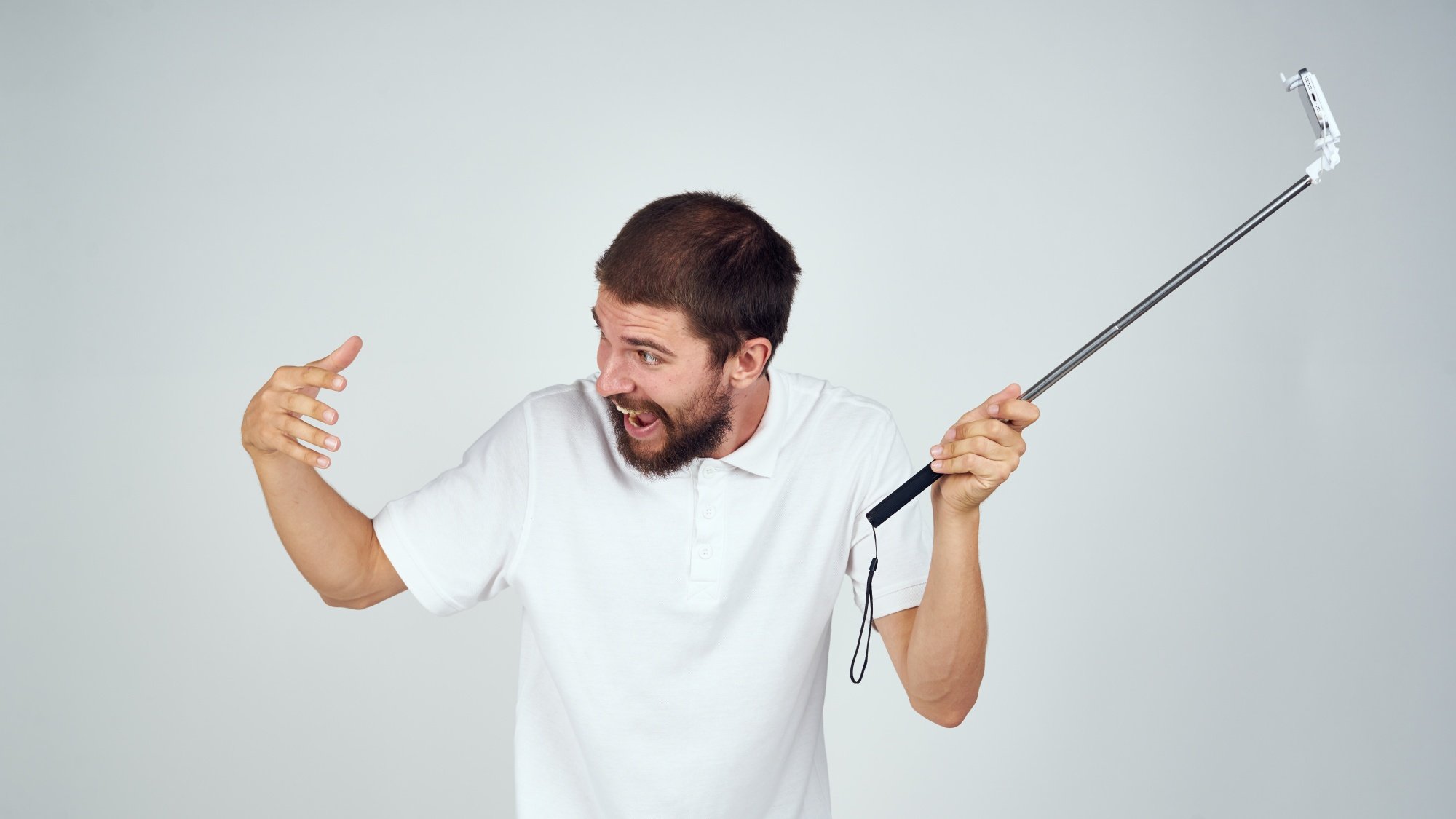 man holding a selfie stick on a light background